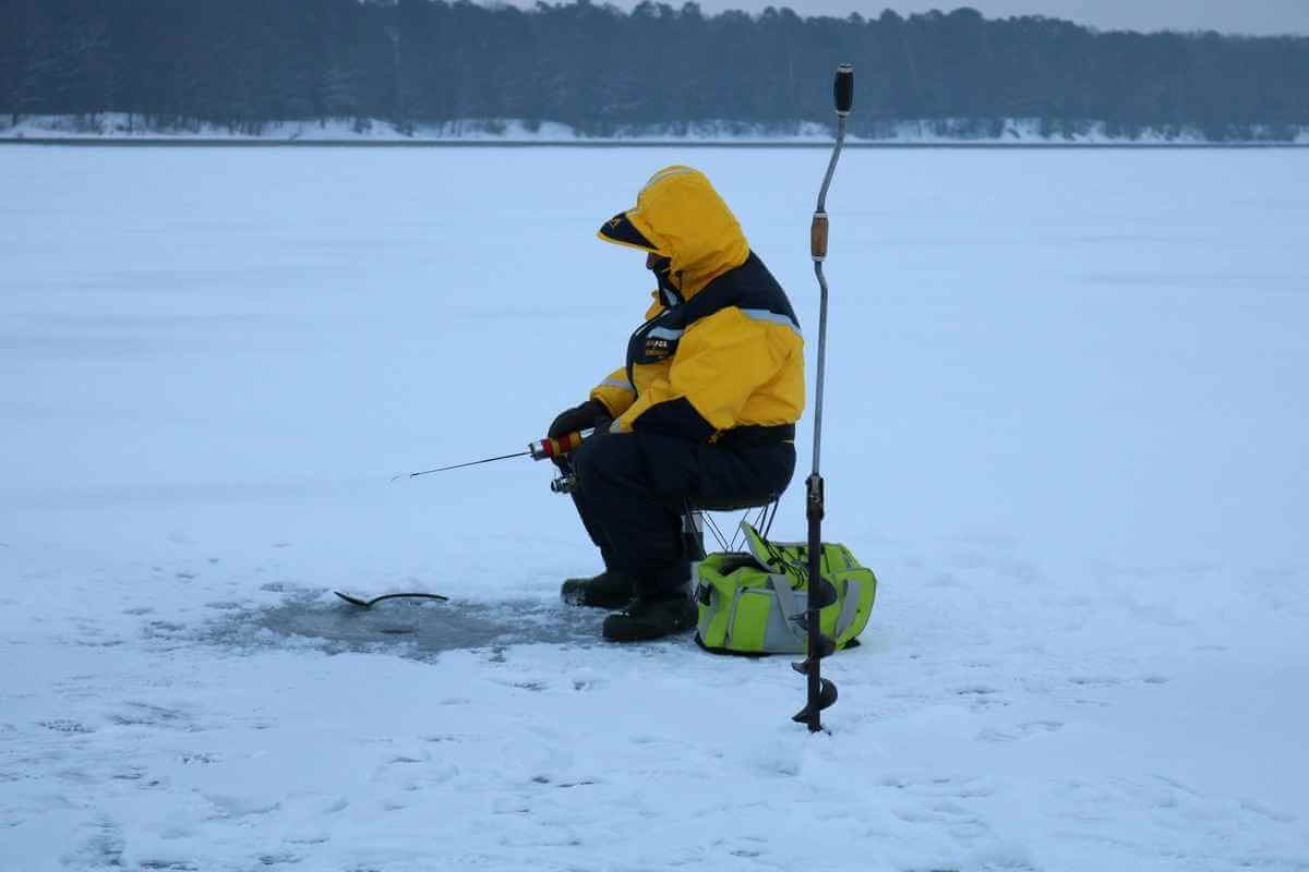 Anglers ice fishing on a frozen lake under a winter sky.