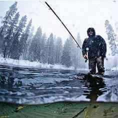 An angler preparing tackle beside a clear Irish stream surrounded by rocks and lush green foliage.